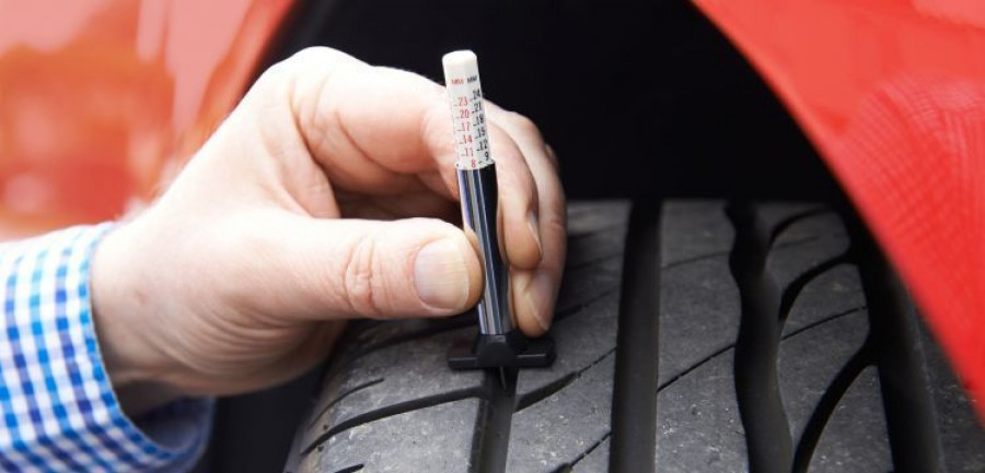 Close-up Of Man Checking Tread On Car Tyre With Gauge