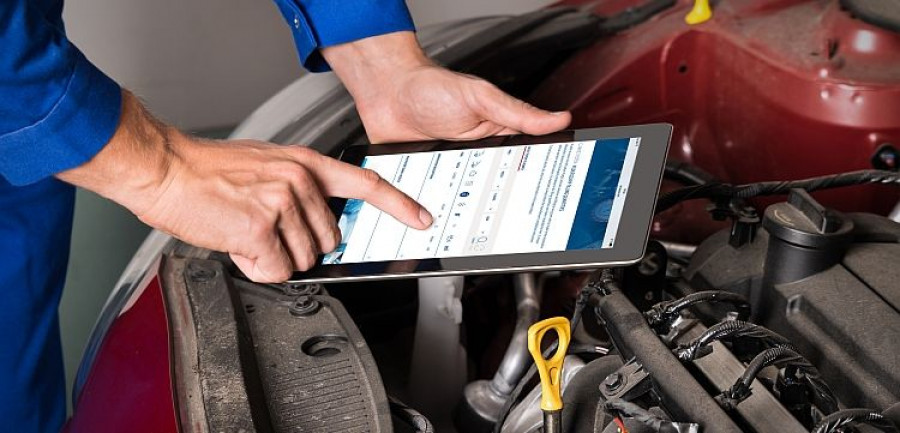 Mechanic Using Digital Tablet While Examining Car Engine
