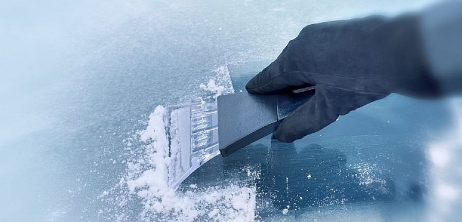 winter driving - scraping ice from a windshield
